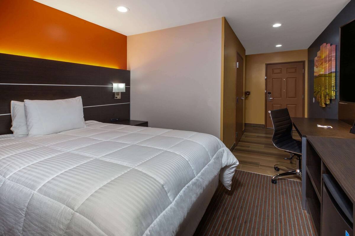 Una habitación de hotel con una cama grande, un escritorio y una silla.