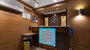 A modern restroom with wooden paneling, a wall-mounted air conditioner, a decorative light panel, and a disabled access sign.
