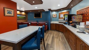 A restaurant with a marble counter, blue patterned chairs, and wooden cabinets.