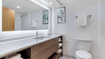 Une salle de bain moderne avec un grand miroir, deux lavabos, des toilettes et une douche.