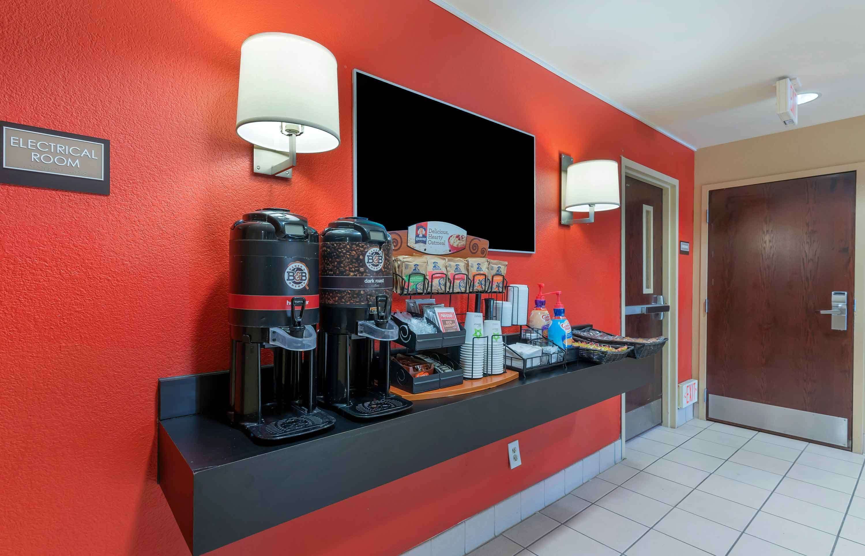 A coffee station with multiple coffee makers, a beverage dispenser, and a sign indicating an electrical room.