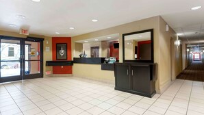 En hotellobby med en receptionsdisk, en stor spegel och en utrymningsskylt.
