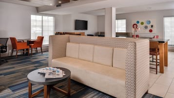 A modern hotel room with a sofa, a dining table, and chairs.
