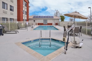 Un espace piscine comprenant deux piscines, des chaises longues et un parasol.