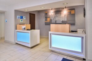 A reception area with two reception desks, a wooden door, and a wall-mounted sign.