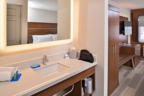 A modern hotel bathroom with a large mirror, a sink, and a vanity.