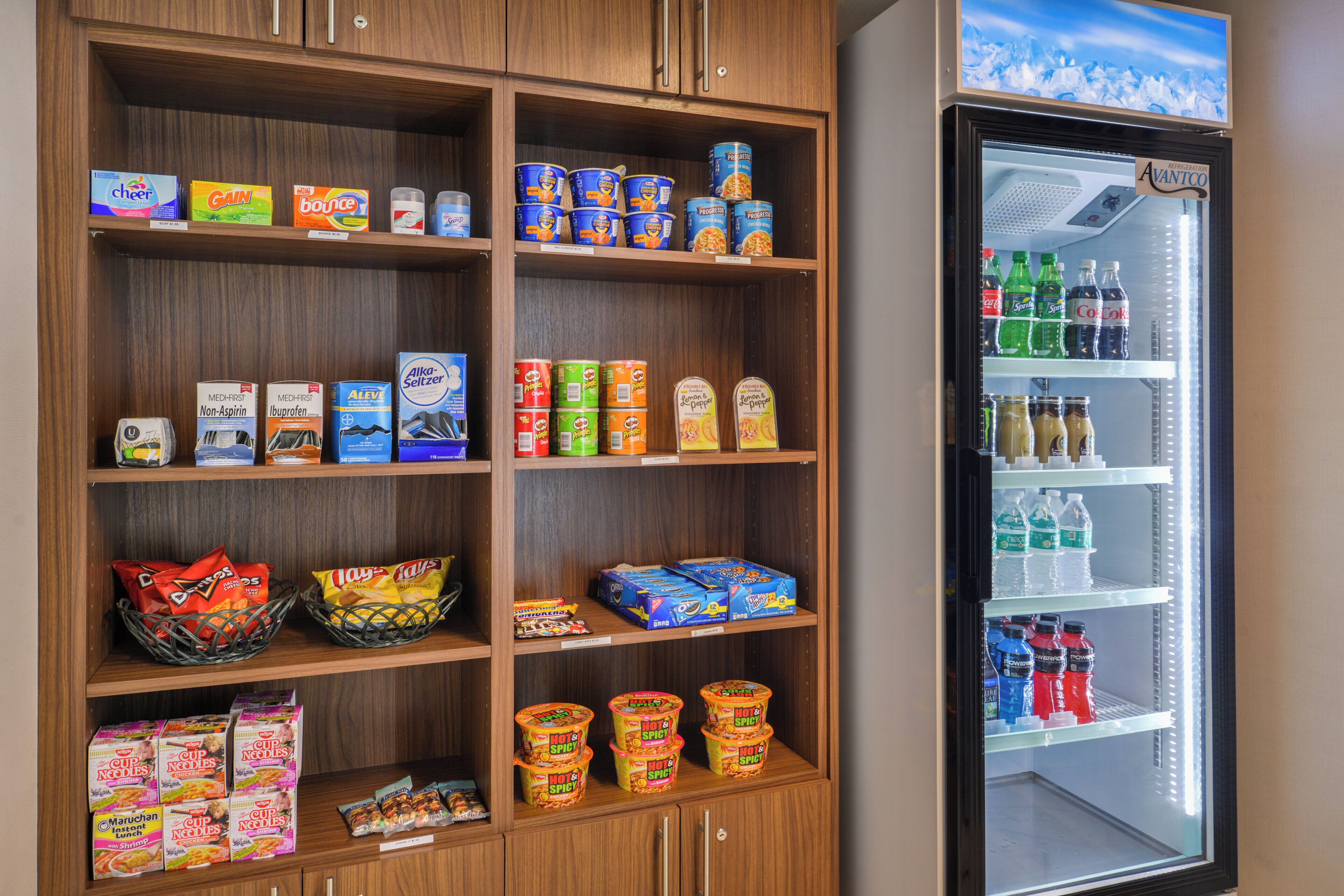 A refrigerated display with various beverages and a shelf stocked with snacks and food items.