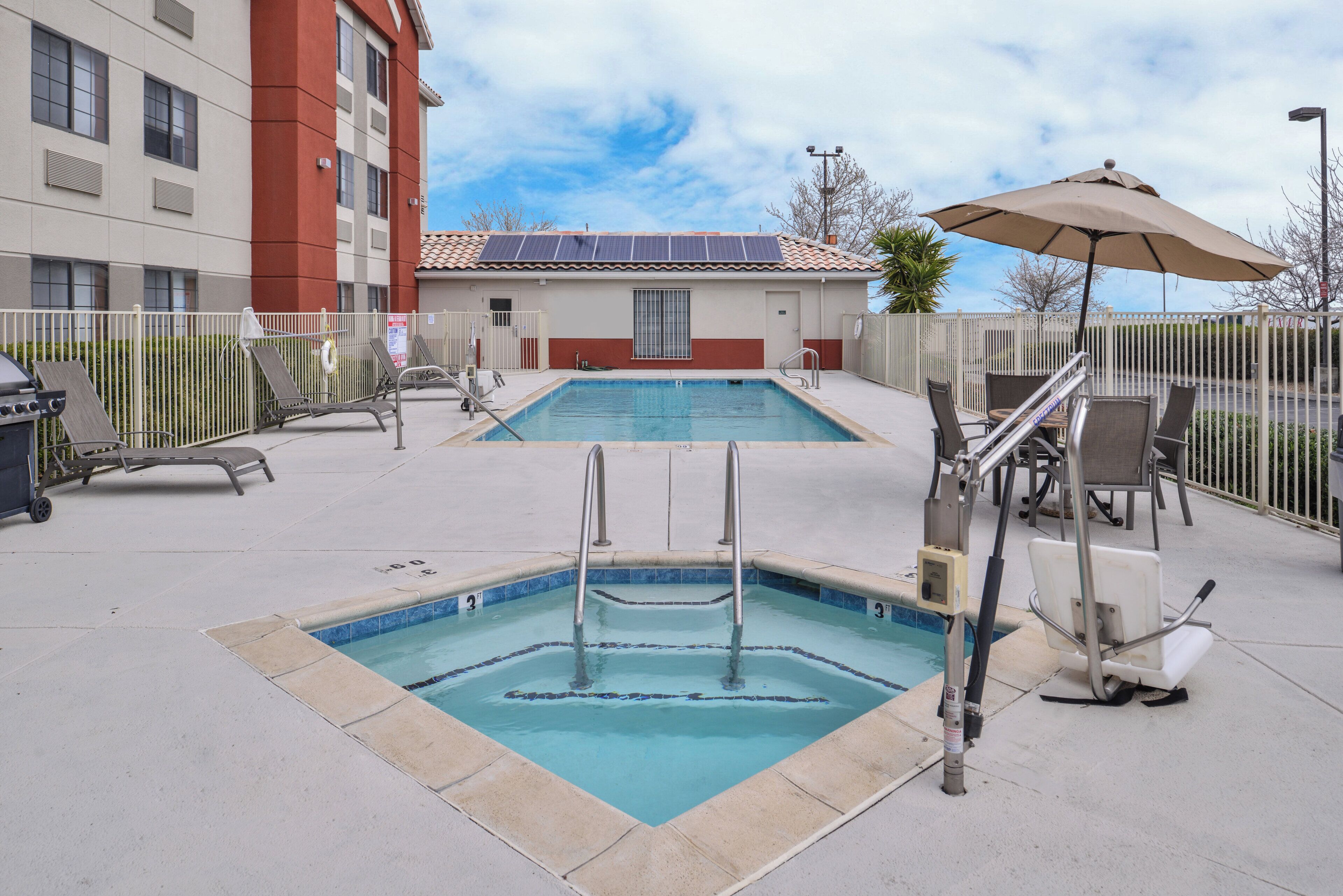 A swimming pool area with a diving board, lounge chairs, and a covered seating area.