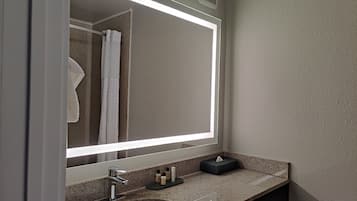 A bathroom with a large mirror, a sink, and a towel rack.
