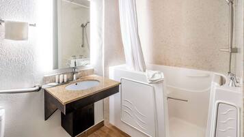 A modern bathroom with a sink, mirror, shower, and bathtub.
