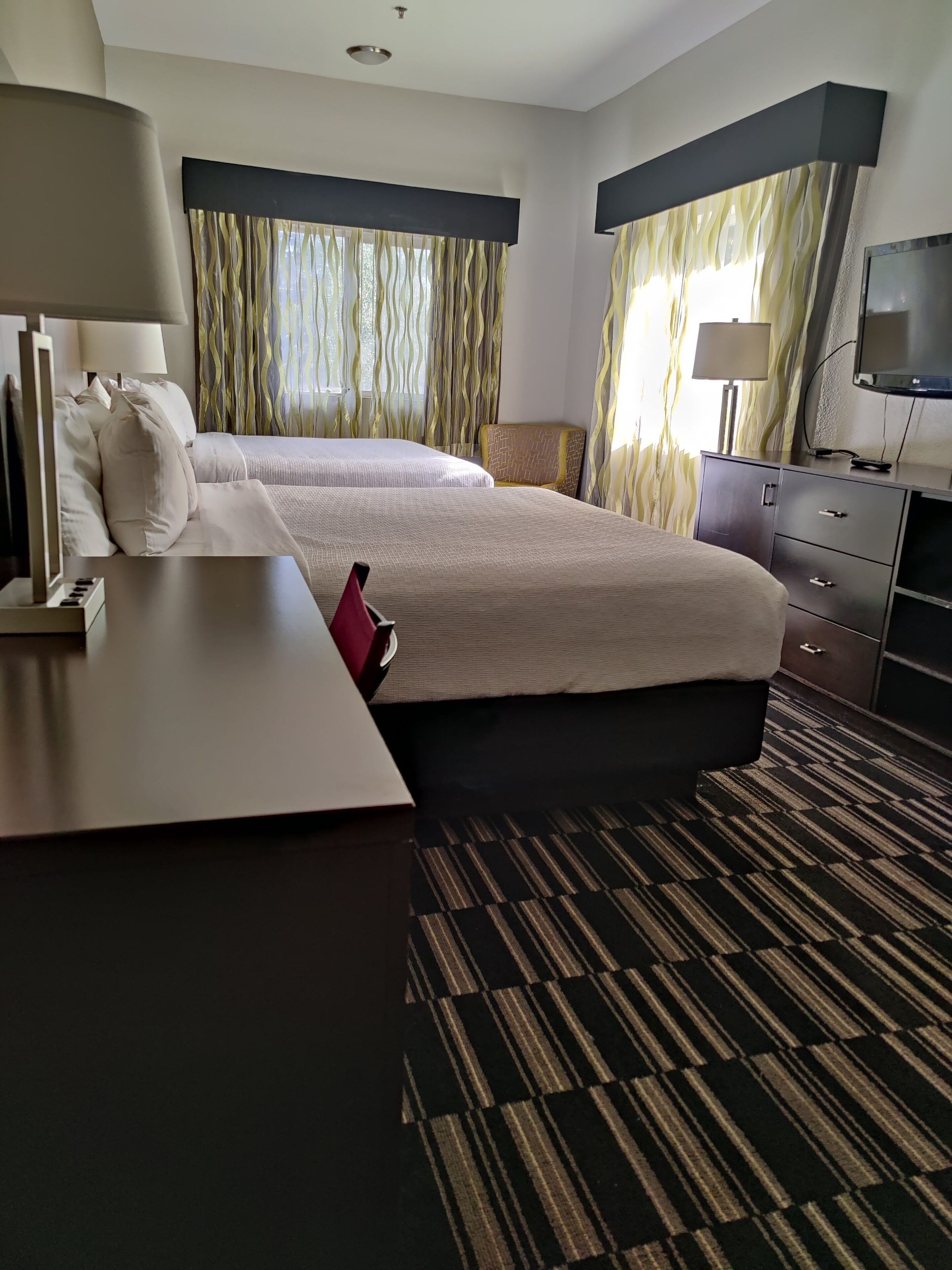 A hotel room with two beds, a desk, a television, and a wardrobe.