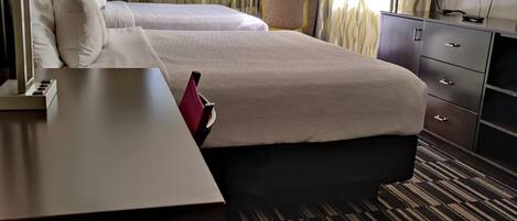 A hotel room with two beds, a desk, a television, and a wardrobe.