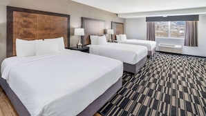 Une chambre d’hôtel avec deux lits, une grande fenêtre avec des rideaux, un sol recouvert de moquette et un climatiseur fixé au mur.