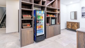Une cuisine moderne dotée de meubles de rangement en bois intégrés, d’un réfrigérateur rempli de boissons et de meubles dont le motif rappelle un parquet en chevrons.
