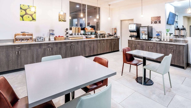 Une cuisine moderne avec un coin repas, comprenant un grand îlot central, des meubles de couleur sombre et un éclairage suspendu.