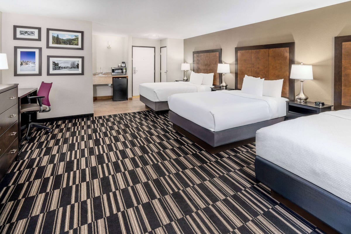 Een hotelkamer met twee bedden, een bureau, een stoel en een magnetron.
