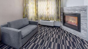 Un salon moderne avec un canapé gris, une cheminée et des rideaux à motifs.