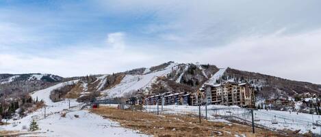 A ski resort with a mountain backdrop, ski lifts, and a large lodge with multiple floors.