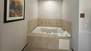 Une salle de spa avec une grande baignoire, un tableau encadré au mur et un panneau indiquant la durée du soin.
