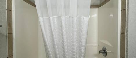 A shower with a white curtain, a handheld showerhead, and a towel rack.