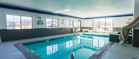 An indoor swimming pool with clear windows, a tiled floor, and a no diving sign.