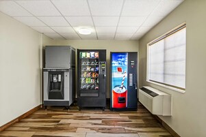 A room with a vending machine, a water dispenser, and a refrigerator.