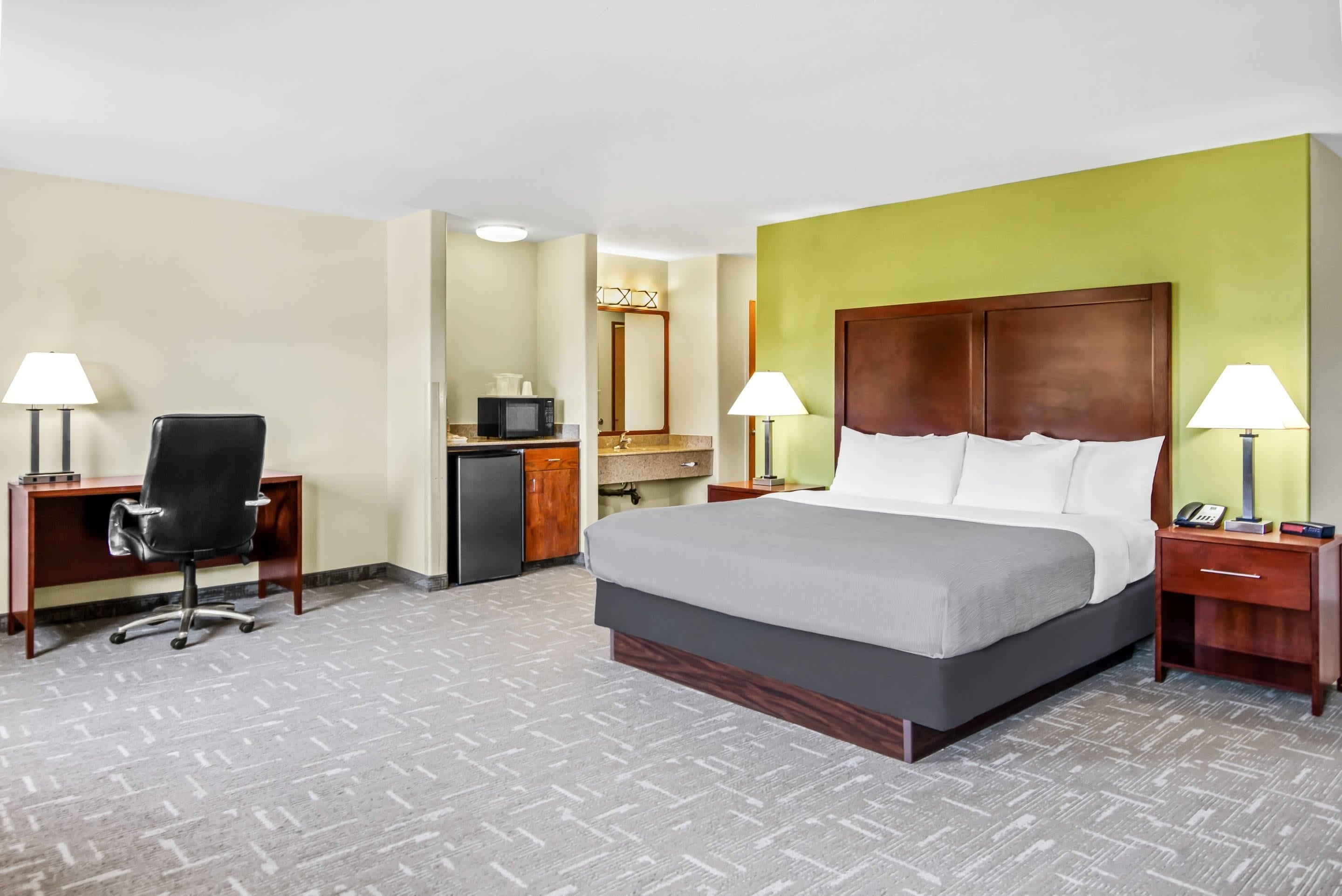 A hotel room with a bed, desk, chair, and a microwave.