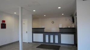 A reception area with a reception desk, a clock on the wall, and a fire extinguisher mounted on the wall.
