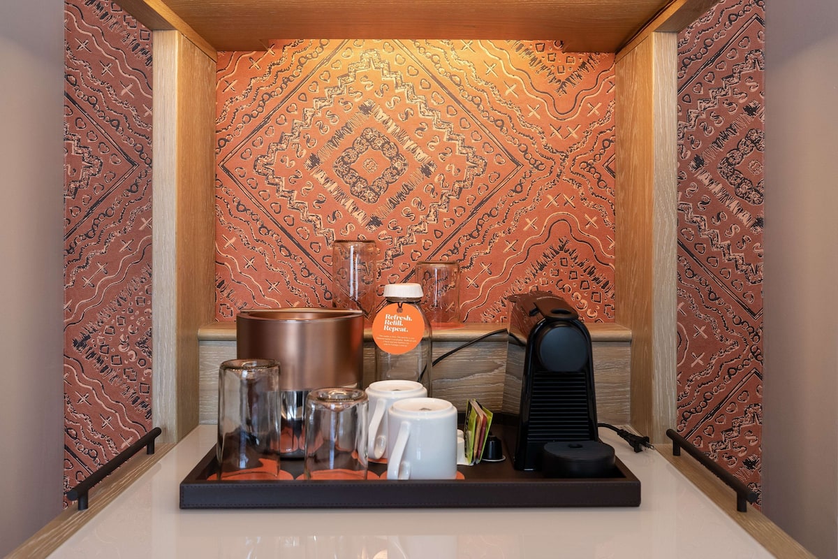 A coffee station with a coffee maker, cups, and a kettle.