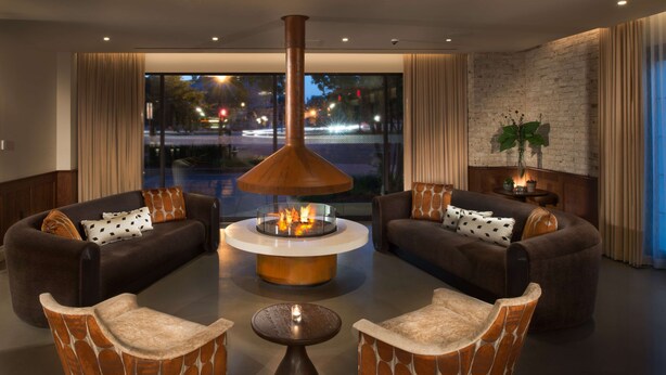 A modern lounge area with a central fire feature, comfortable seating, and a view of the cityscape. - Canopy by Hilton Washington Embassy Row (Washington)
