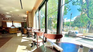 A spacious indoor area with large windows, a dining table with chairs, and a view of the outdoor seating area. - Canopy by Hilton Washington Embassy Row (Washington)