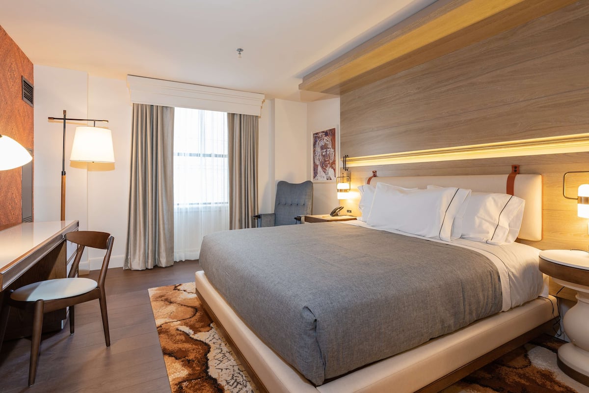 A modern hotel room with a large bed, a desk, and a chair.