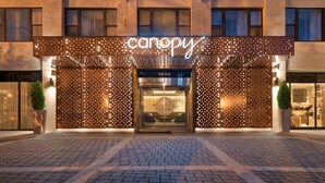 A hotel entrance with a canopy sign, a glass door, and a brick-paved entrance area. - Canopy by Hilton Washington Embassy Row (Washington)