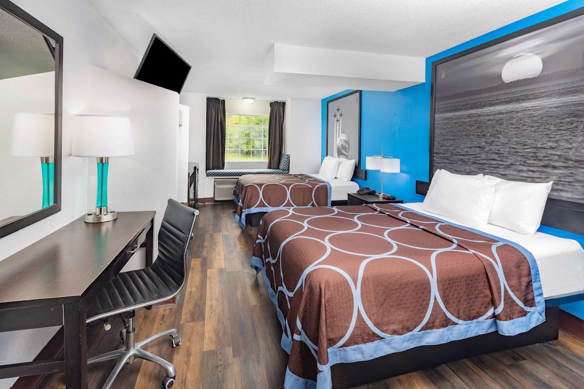 Habitación de hotel con cama, escritorio, silla, televisión y ventana.
