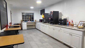 Una cocina con armarios blancos, una cafetera y un ventanal.