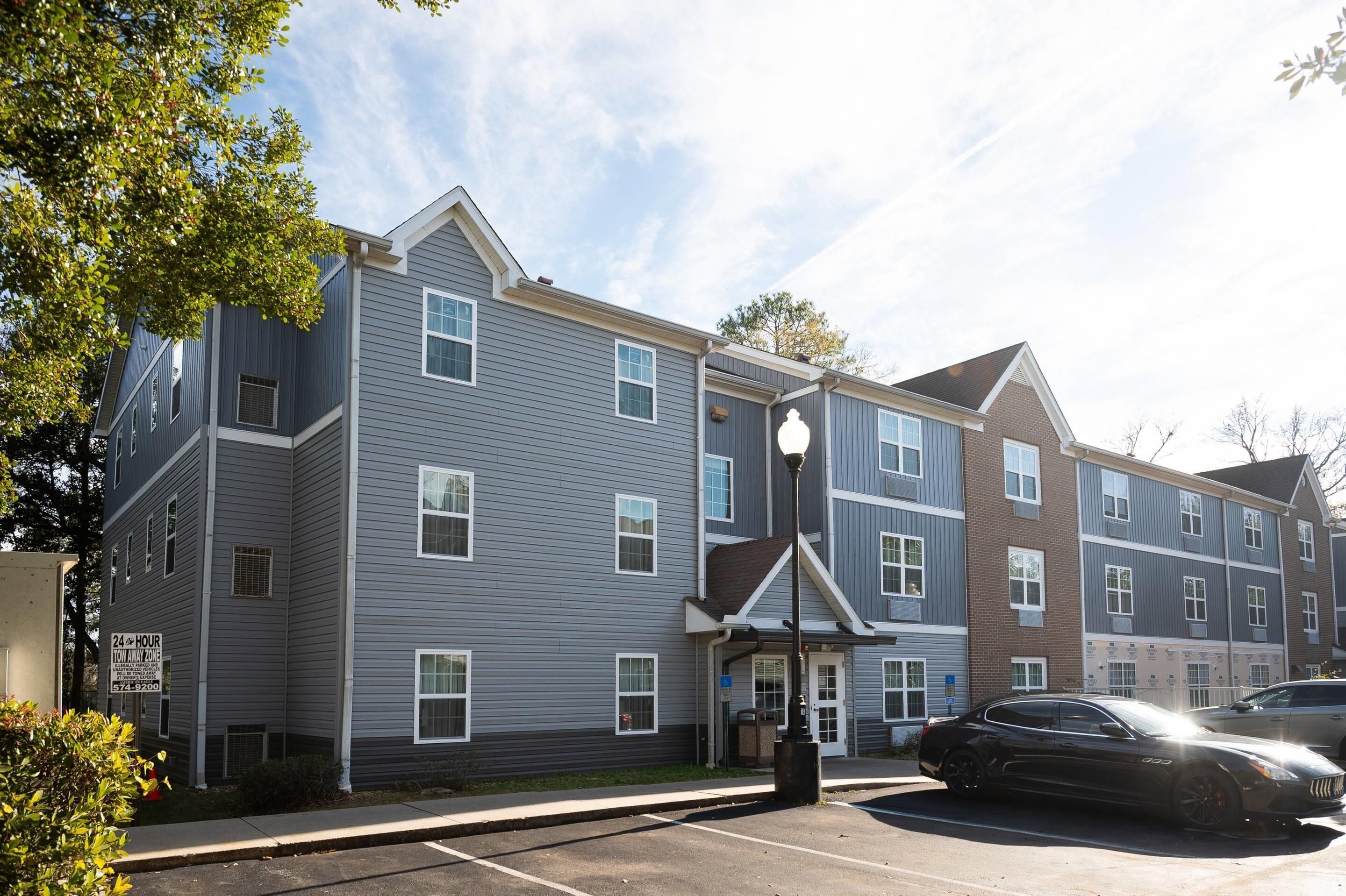 A multi-story residential building with a parking lot and a street lamp.