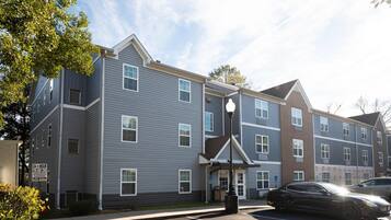 A multi-story residential building with a parking lot and a street lamp.