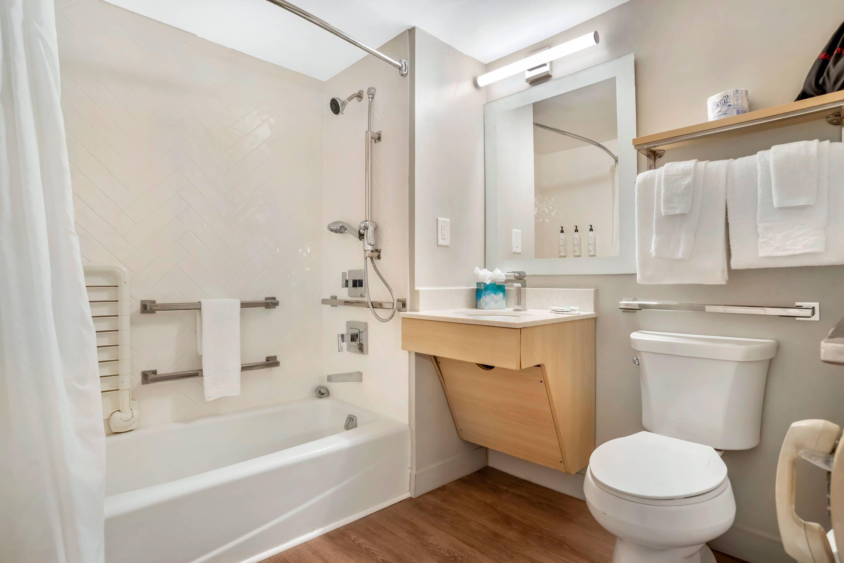 A modern bathroom with a bathtub, toilet, and vanity.