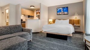 A hotel room with a bed, a sofa, a desk, a lamp, and a picture on the wall. - MainStay Suites (Tallahassee)
