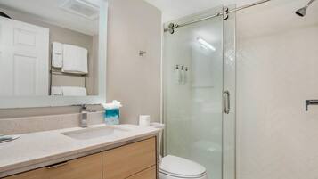 Ein Badezimmer mit Duschkabine, Waschbecken mit Spiegel und Toilette.