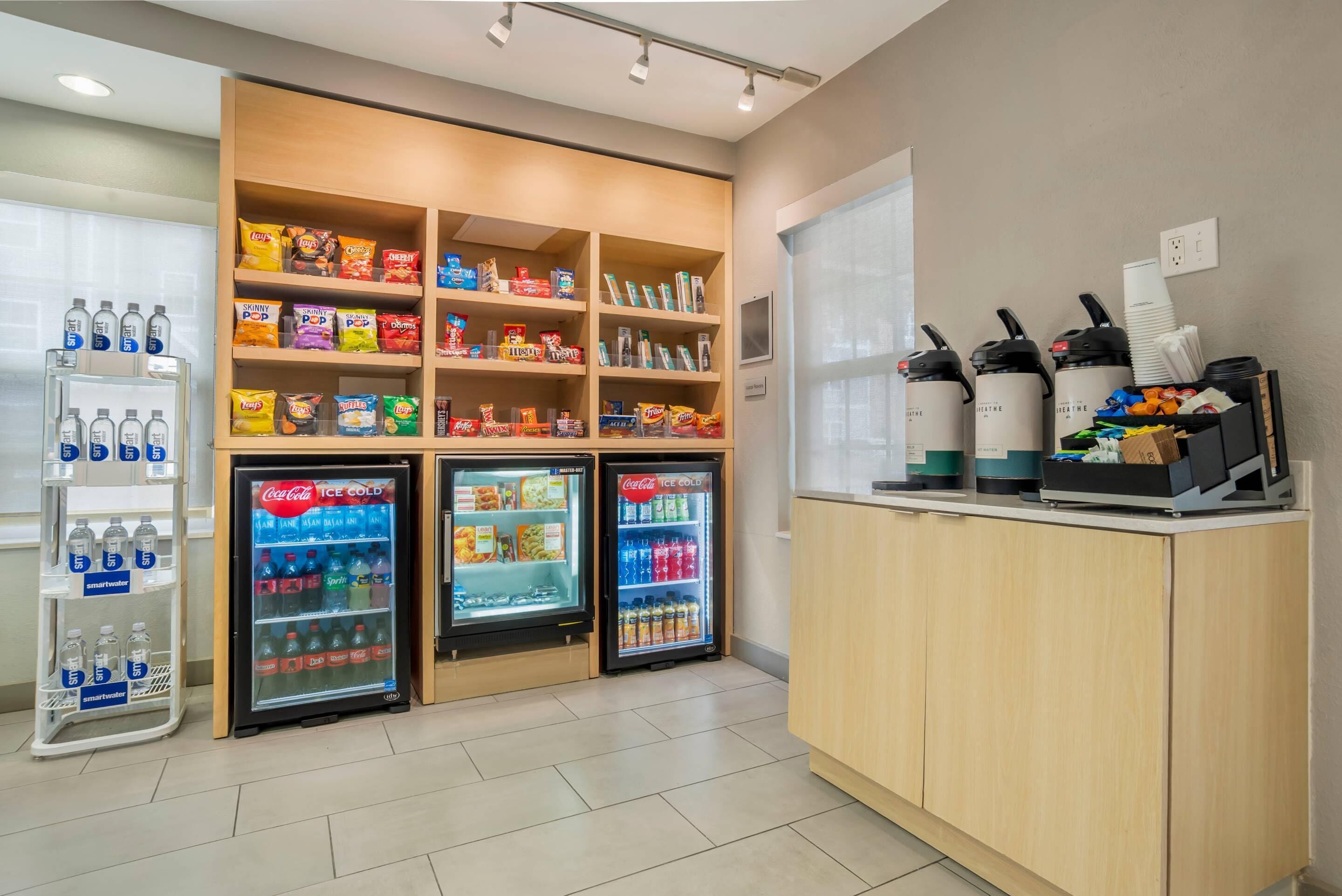 Een hotel receptie met snackplanken, drankautomaat en een balie met telefoons en bekers.
