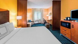 Une chambre d’hôtel avec un grand lit, un bureau, une chaise, une télévision et un four à micro-ondes.