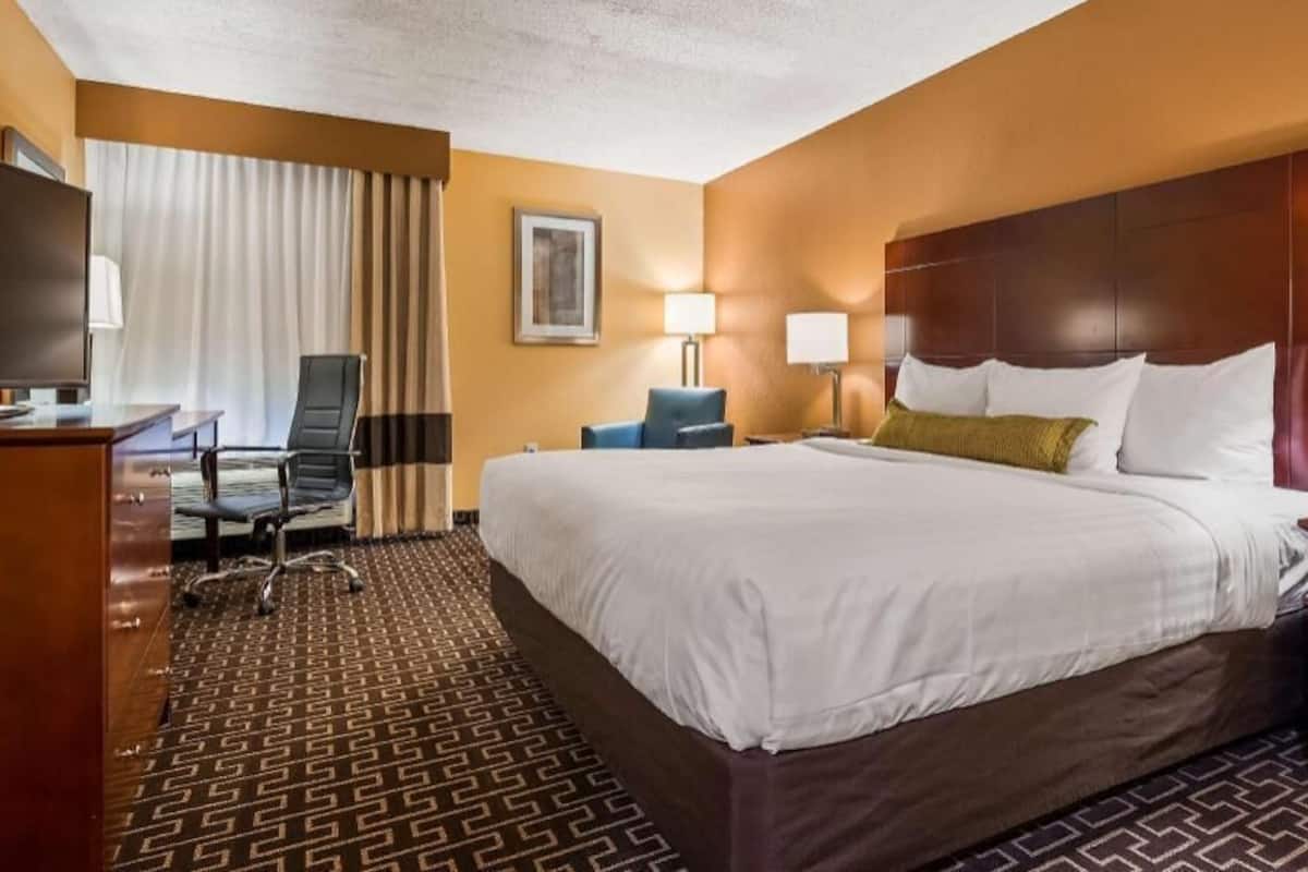 Habitación de hotel con una cama grande, un escritorio, una silla y un televisor.