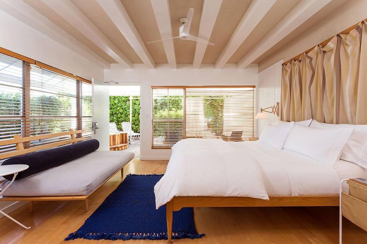 Une chambre avec un lit, un banc et une vue sur la verdure.