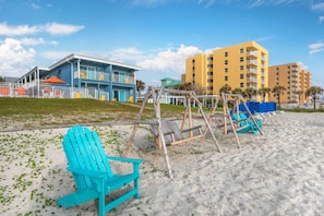 A beach with a blue building, a yellow building, and a swing set. - Coconut Palms Beach Resort II, an Ascend Collection Hotel (New Smyrna Beach)