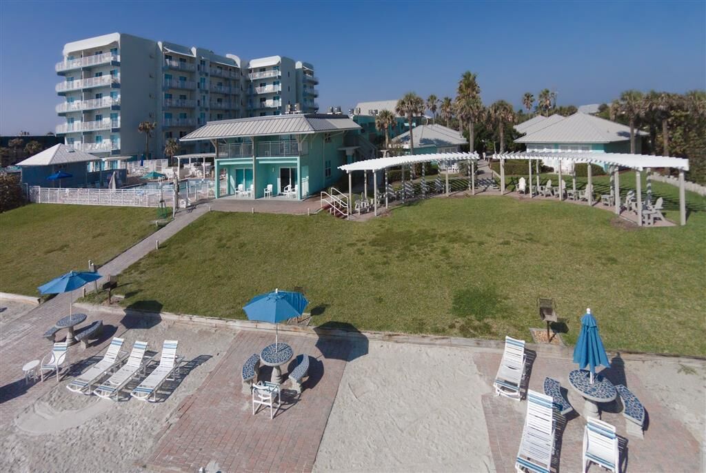 Un hotel con zona de piscina, mobiliario exterior y un edificio con varios balcones.