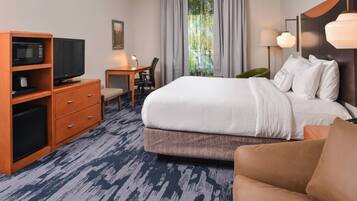 A hotel room with a bed, a TV, a desk, and a chair.