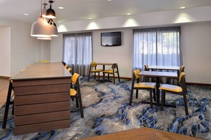 A conference room with a long table, chairs, a flat-screen TV, and a patterned carpet.