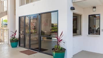 A building entrance with a glass door, potted plants, and a clear view of the outside.