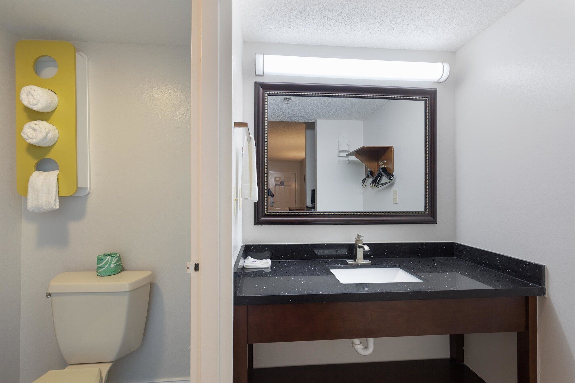 Un baño con un lavabo negro, un espejo y un inodoro.